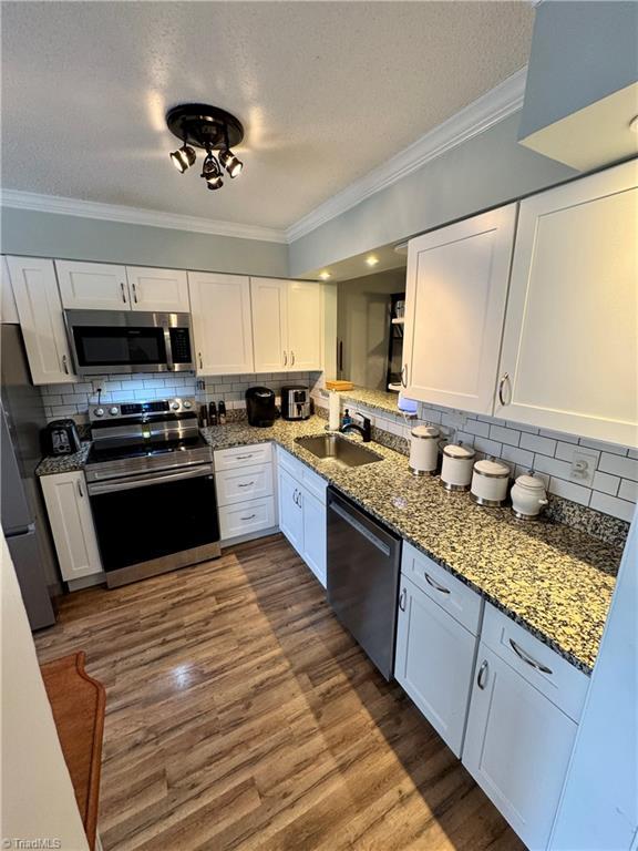 kitchen with sink, crown molding, white cabinets, and appliances with stainless steel finishes