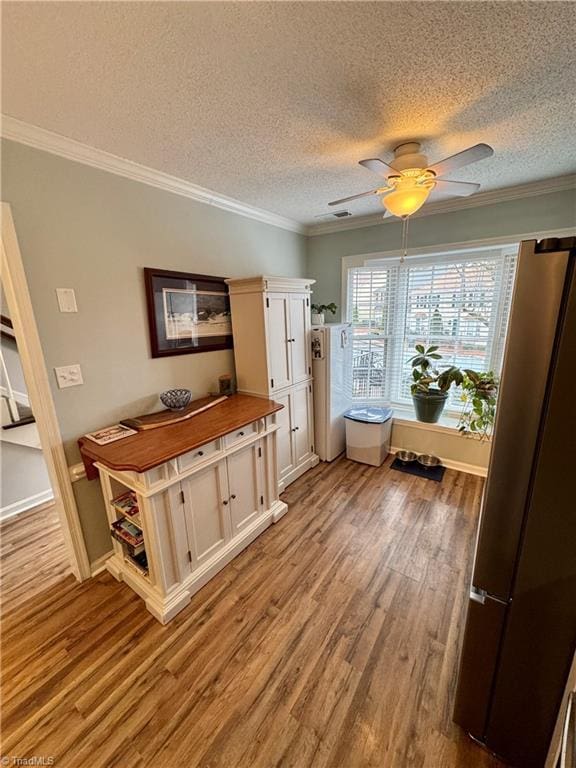 kitchen featuring white cabinetry, stainless steel fridge, ornamental molding, ceiling fan, and light hardwood / wood-style floors