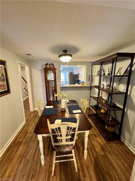 dining space with dark hardwood / wood-style floors and a textured ceiling