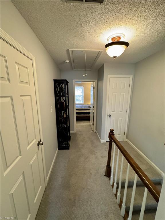 hall featuring carpet floors and a textured ceiling