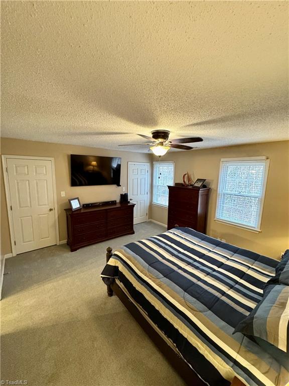 bedroom with carpet flooring, a textured ceiling, and ceiling fan