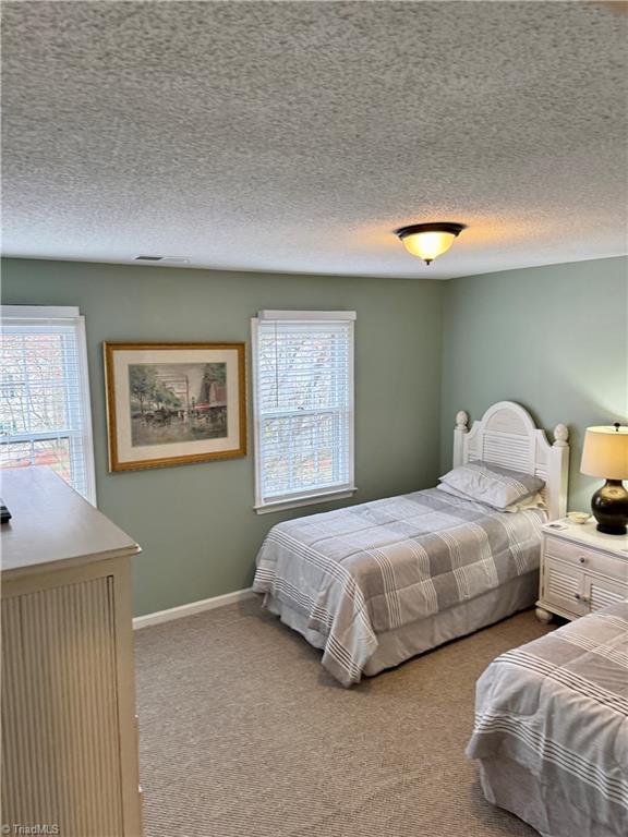 bedroom with light colored carpet and a textured ceiling