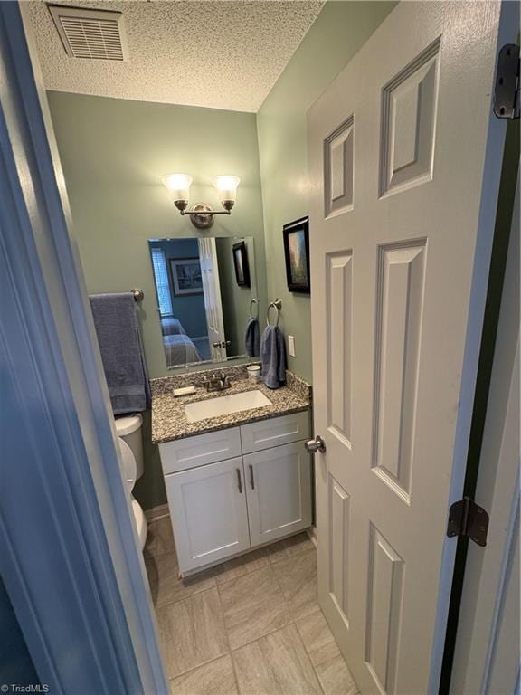 bathroom with vanity, toilet, and a textured ceiling