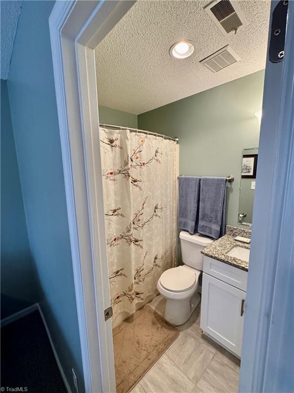 bathroom featuring vanity, toilet, and a textured ceiling