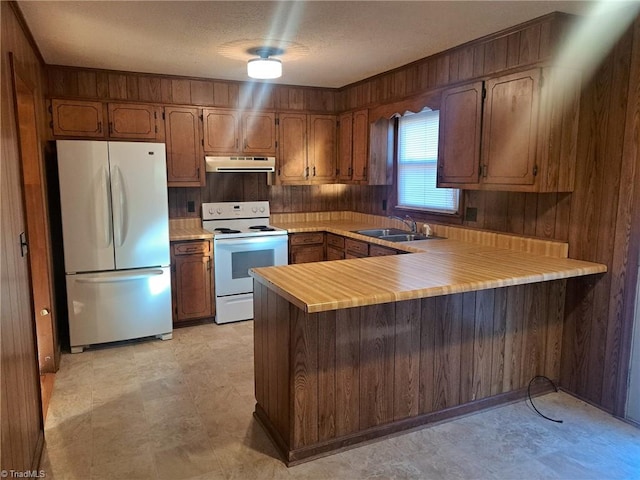 kitchen with kitchen peninsula, a textured ceiling, white range with electric stovetop, sink, and fridge