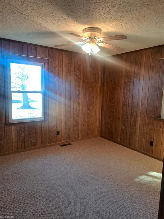 spare room with ceiling fan and wood walls