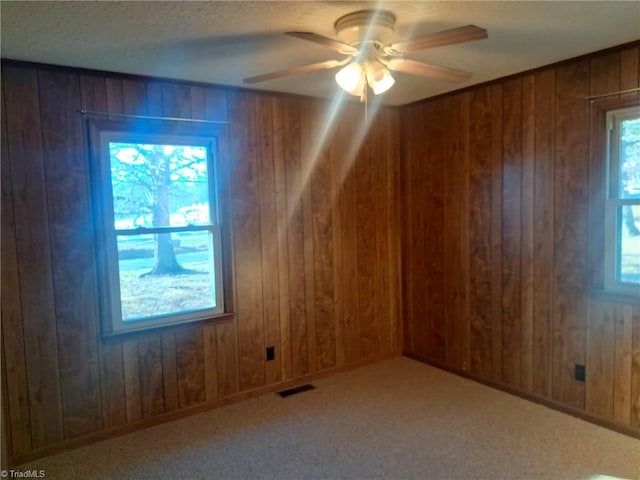 bonus room featuring carpet flooring, ceiling fan, and wood walls