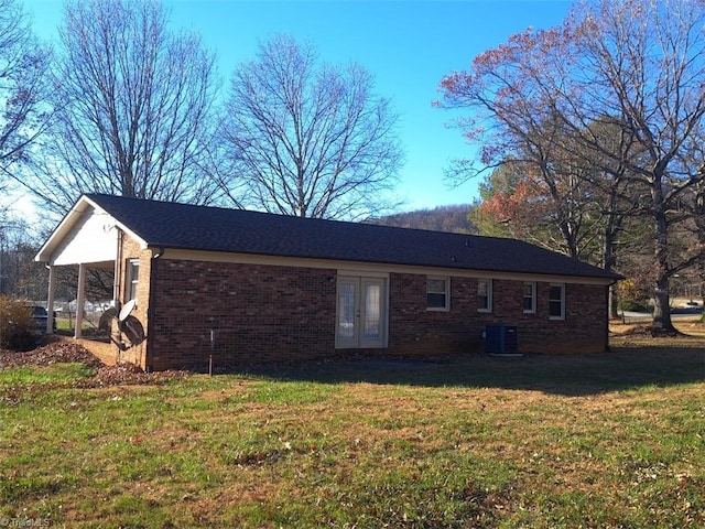 rear view of house with french doors, central AC, and a lawn