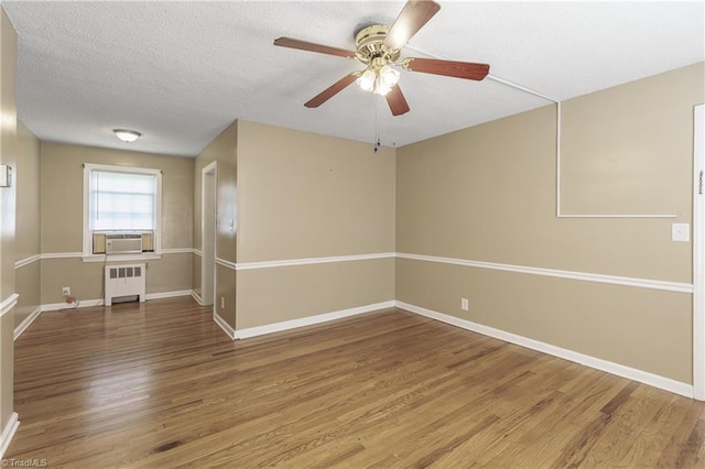 spare room with radiator, ceiling fan, cooling unit, wood-type flooring, and a textured ceiling