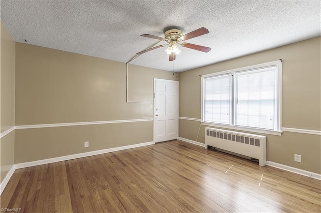 spare room featuring radiator heating unit, a textured ceiling, ceiling fan, and light hardwood / wood-style flooring