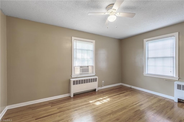 unfurnished room with light wood-type flooring, radiator heating unit, and plenty of natural light