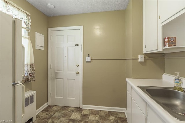 laundry room with radiator, sink, and a textured ceiling