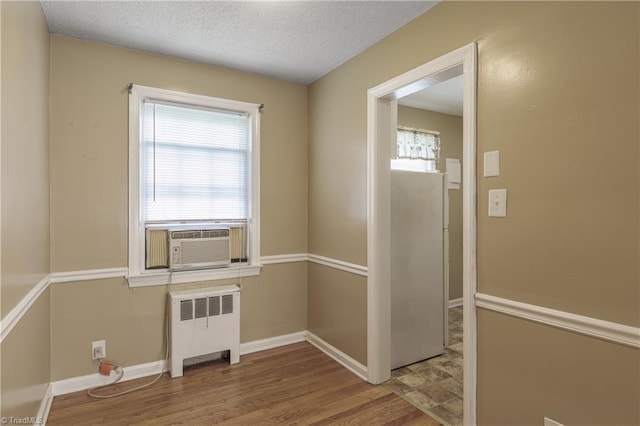 interior space with cooling unit, radiator, light hardwood / wood-style floors, and a textured ceiling