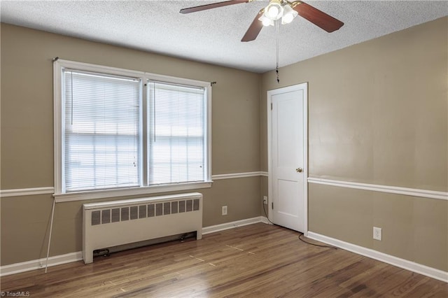 spare room featuring wood-type flooring, radiator heating unit, ceiling fan, and a textured ceiling