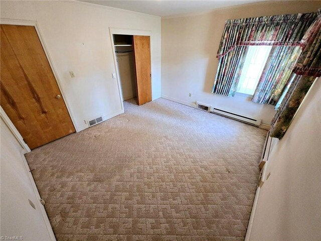 3015 S NC Highway 87, Graham, NC 27253 - unfurnished bedroom featuring a baseboard radiator, carpet flooring, crown molding, baseboards, and a closet