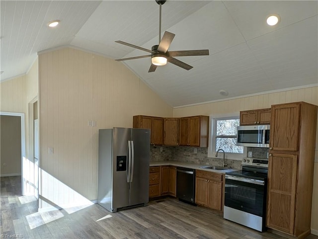 kitchen with wood finished floors, vaulted ceiling, a sink, and appliances with stainless steel finishes