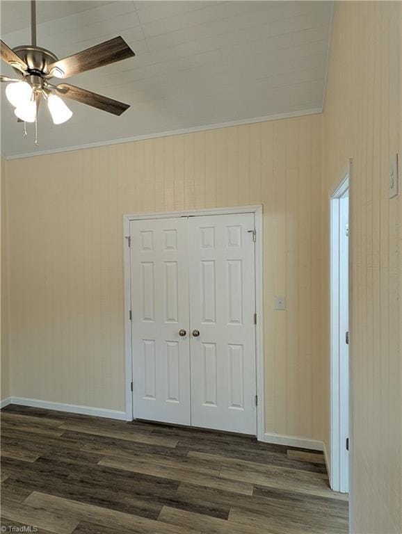 interior space featuring wooden walls, ornamental molding, a closet, and dark wood finished floors