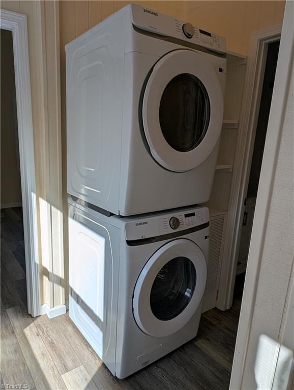 laundry room featuring stacked washer and dryer, laundry area, and wood finished floors