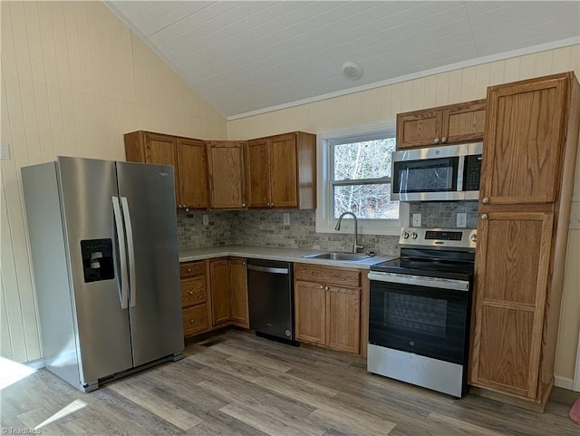 kitchen with lofted ceiling, decorative backsplash, stainless steel appliances, a sink, and wood finished floors