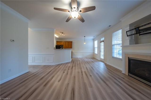 unfurnished living room featuring light wood-type flooring, ceiling fan, and crown molding