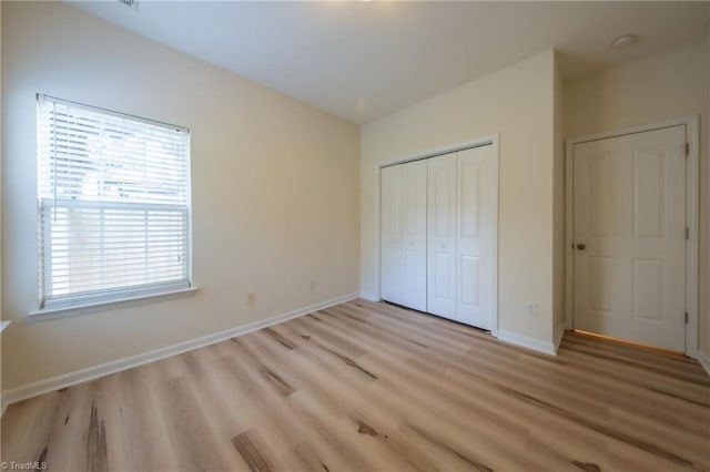 unfurnished bedroom with light wood-type flooring and a closet