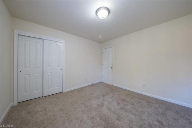 unfurnished bedroom with light colored carpet and a closet