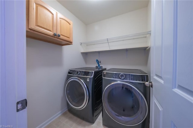 clothes washing area featuring washing machine and dryer and cabinets