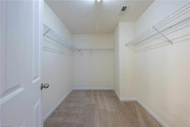 walk in closet featuring light colored carpet