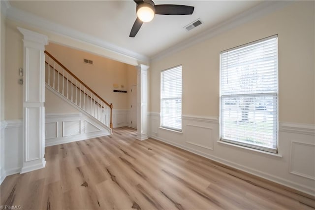 unfurnished living room featuring decorative columns, light hardwood / wood-style flooring, and crown molding