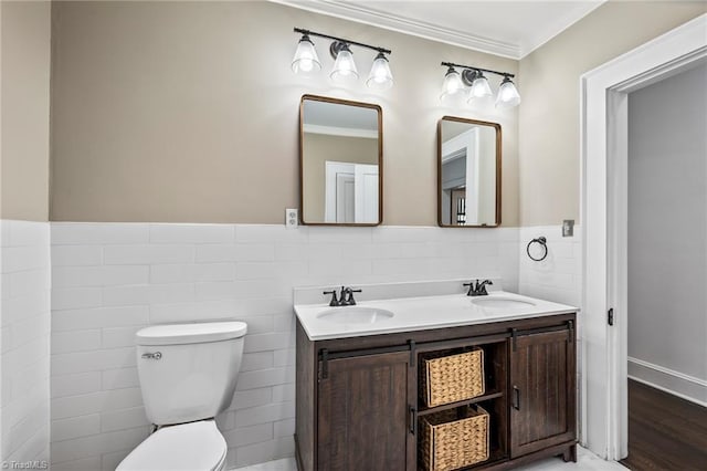 bathroom featuring vanity, toilet, crown molding, and tile walls