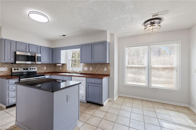 kitchen featuring light tile patterned floors, tasteful backsplash, visible vents, appliances with stainless steel finishes, and a sink