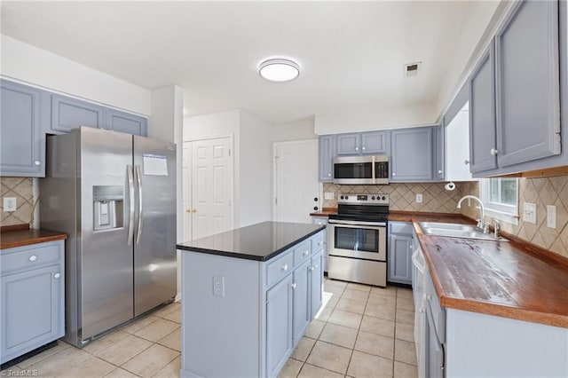 kitchen featuring a center island, stainless steel appliances, a sink, and light tile patterned flooring