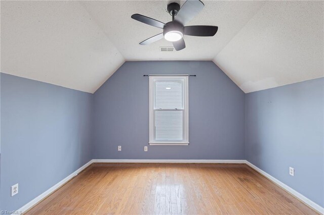 additional living space with visible vents, a textured ceiling, baseboards, and hardwood / wood-style flooring