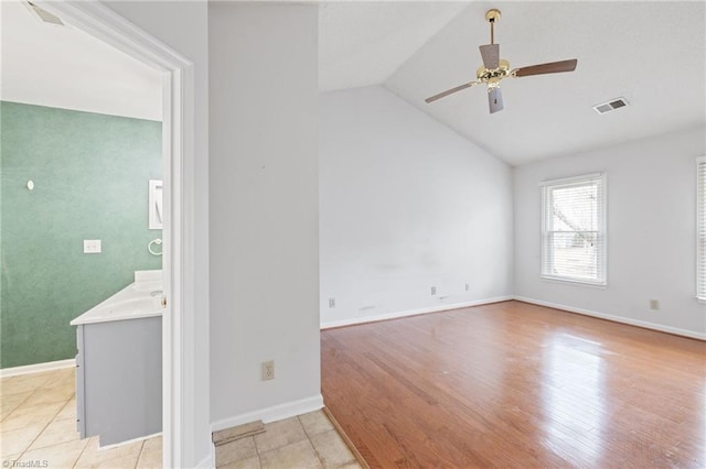 empty room featuring visible vents, baseboards, vaulted ceiling, a ceiling fan, and light wood-type flooring