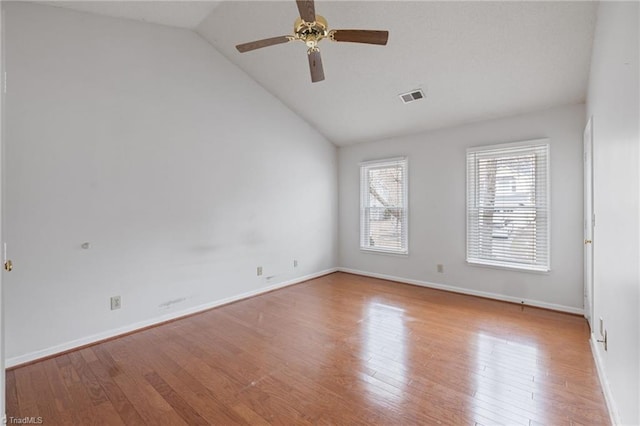 spare room featuring baseboards, visible vents, a ceiling fan, wood finished floors, and vaulted ceiling