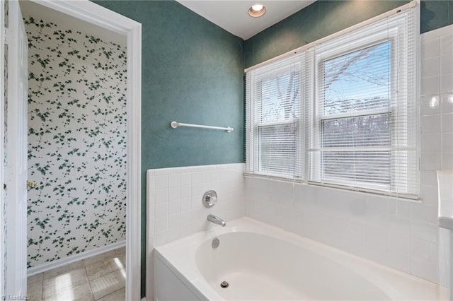 bathroom featuring tile patterned flooring, a bath, and baseboards