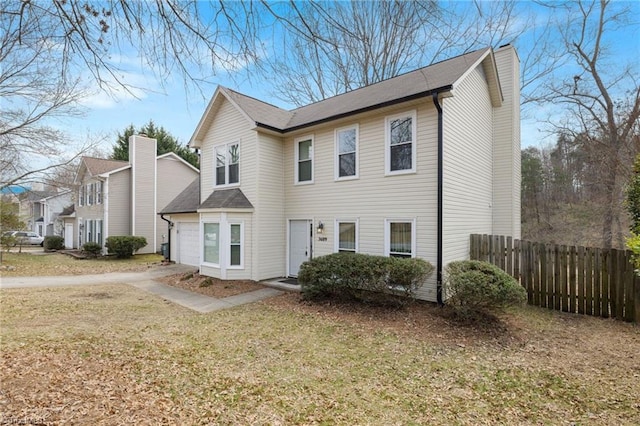 view of front of property with concrete driveway, a front yard, and fence