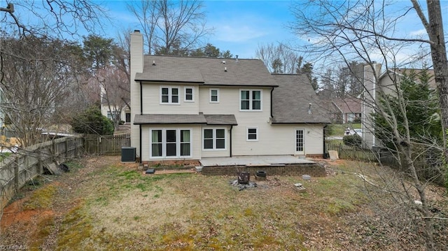 back of property with central air condition unit, a patio area, a fenced backyard, and a chimney