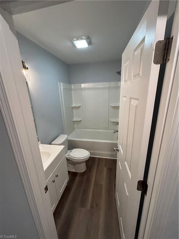 full bathroom featuring vanity, hardwood / wood-style flooring, bathtub / shower combination, and toilet