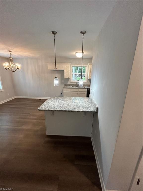 kitchen featuring sink, dark hardwood / wood-style floors, a kitchen bar, decorative light fixtures, and kitchen peninsula