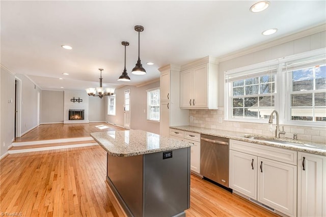 kitchen featuring tasteful backsplash, open floor plan, a kitchen island, a sink, and dishwasher