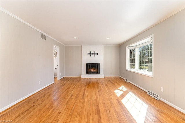 unfurnished living room featuring light wood-style flooring, a fireplace, visible vents, and crown molding