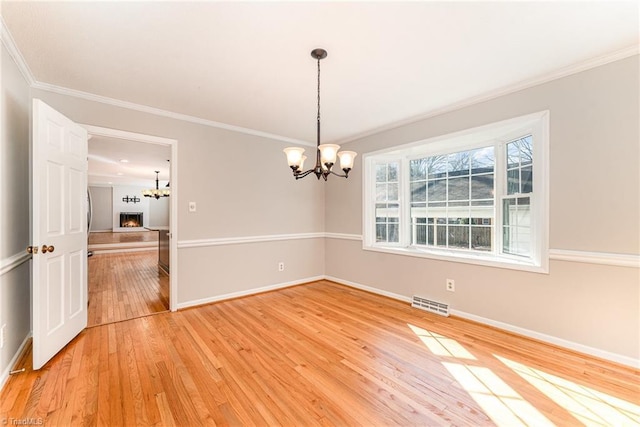 unfurnished dining area with a notable chandelier, visible vents, light wood-style floors, baseboards, and ornamental molding