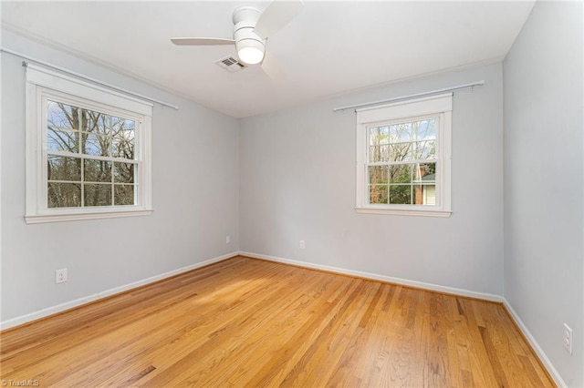 spare room featuring light wood finished floors, a ceiling fan, visible vents, and baseboards