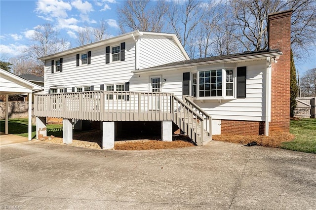 view of front facade featuring a deck, driveway, and a chimney