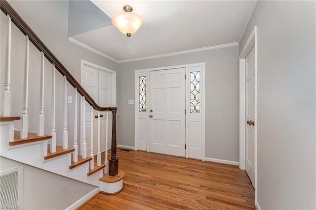 entryway featuring visible vents, crown molding, light wood-style flooring, and stairs