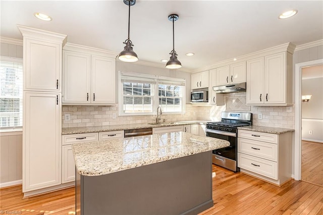 kitchen featuring white cabinets, under cabinet range hood, stainless steel appliances, and a sink