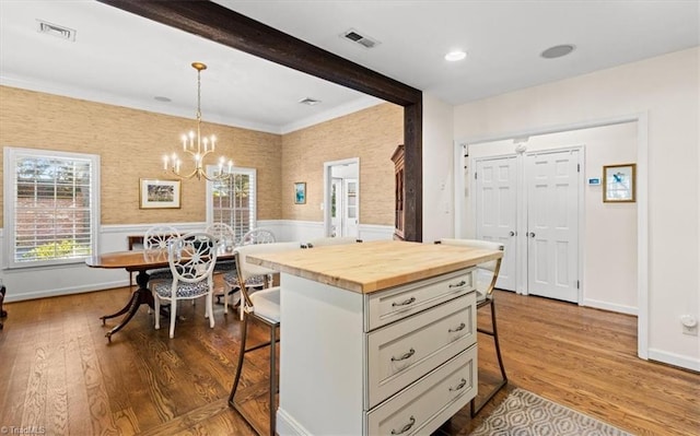 kitchen with butcher block countertops, a breakfast bar, beam ceiling, a kitchen island, and decorative light fixtures