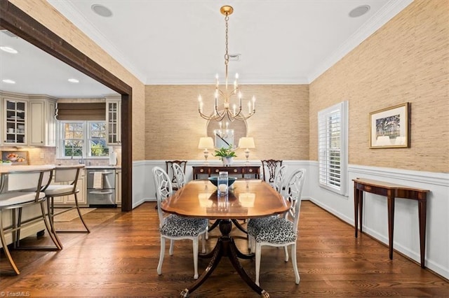 dining area featuring dark wood-type flooring, ornamental molding, and a chandelier