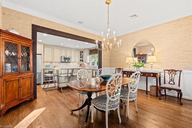 dining area featuring crown molding, a chandelier, and light hardwood / wood-style floors